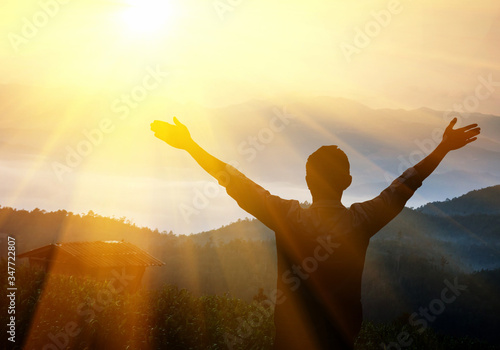 Man with arms raised at sunset. Young man at sunset raises his hands up