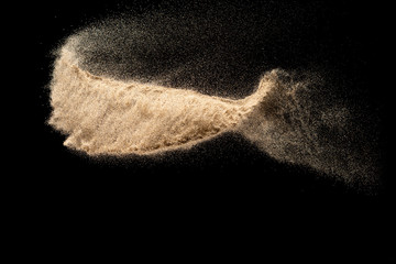 Wall Mural - Brown sand explosion isolated on black background. Freeze motion of sandy dust splash.Sand texture concept.