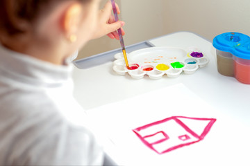 Poster - Hands of a little child drawing a house with watercolors. Children's creativity.