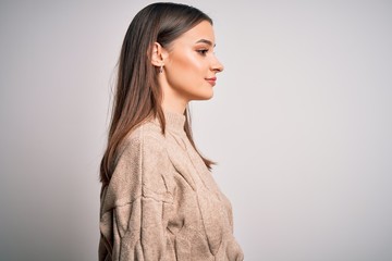 Young beautiful brunette woman wearing casual sweater standing over white background looking to side, relax profile pose with natural face with confident smile.