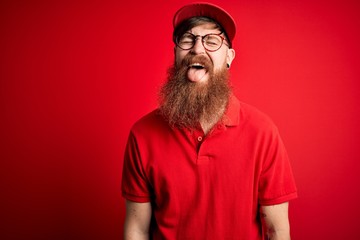 Poster - Young handsome delivery man wearing glasses and red cap over isolated background sticking tongue out happy with funny expression. Emotion concept.