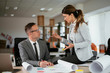 © JustLife - Colleagues in office. Businesswoman and businessman discussing work in office.