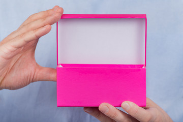 Wall Mural - Open pink box in the men's hands. Front view. Close up. Copy space. Moke up