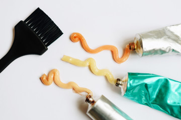 Squeezed out tubes of hair dye and brush on a white background