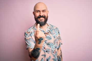 Sticker - Handsome bald man with beard and tattoo wearing casual floral shirt over pink background Beckoning come here gesture with hand inviting welcoming happy and smiling