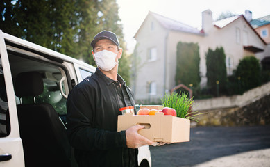 Delivery man courier with face mask delivering groceries in town.