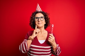 Poster - Middle age curly hair woman wearing birthday funny hat holding party trumpet on celebration serious face thinking about question, very confused idea