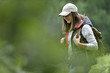 © goodluz - Young woman with backpack hiking in forest