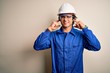 © Krakenimages.com - Young constructor man wearing uniform and security helmet over isolated white background covering ears with fingers with annoyed expression for the noise of loud music. Deaf concept.