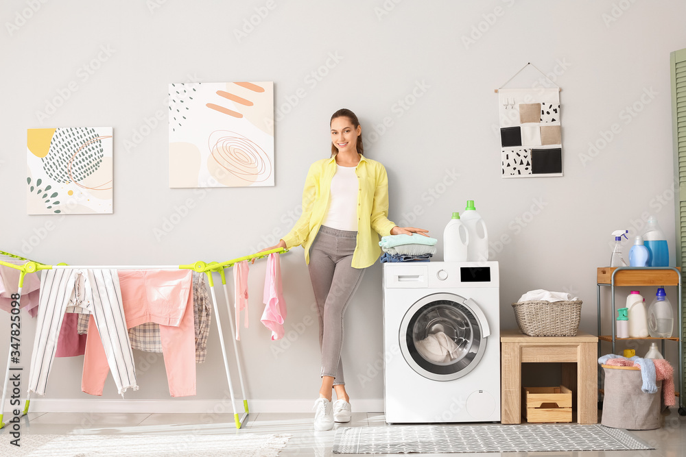 Young woman doing laundry in bathroom