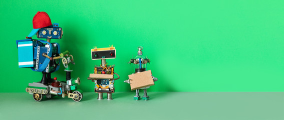 A robot courier delivered orders parcels to buyers. Two robots are holding cardboard boxes with food, possibly with pizza. Copy space for text.