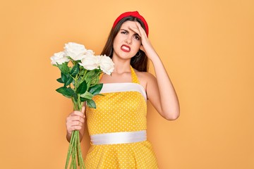 Poster - Young beautiful pin up woman wearing 50s fashion vintage dress holding boquet of roses flowers stressed with hand on head, shocked with shame and surprise face, angry and frustrated. Fear and upset