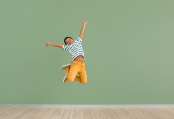 Wall Mural - Little African-American boy jumping against color wall