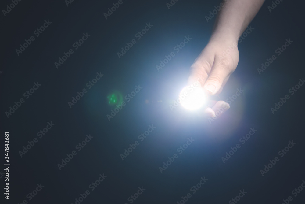 Female hand with modern flashlight on dark background
