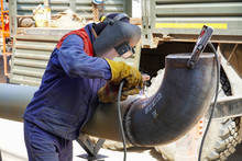 A Professional Welder Works By Manual-arc Welding With An Electrode, And Receives A Weld Of Technological Pipelines DN 250 For An Oil Refinery In Russia
