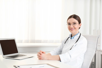 Poster - Portrait of young female doctor in white coat at workplace