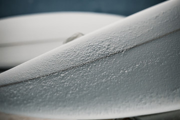 Manufacturing process of a surfboard by a white shirt shaper and black gloves inside his workshop. He uses white foambord, fiberglass cloth and tools to make his board.