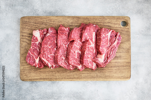 Photo Fresh raw beef steaks on wooden cutting board on gray background