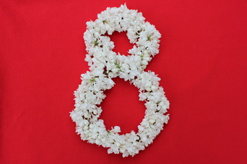 The number 8 is written in white lilac flowers on a red background. The number eight is written in fresh flowers, isolated on red. Arabic numeral lined with flowers.