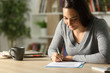 © PheelingsMedia - Girl signing document at home in the night