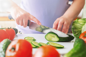 Chef slicing vegetables and cucumber on the table in restaurant. Process of cutting and preparation food in kitchen.