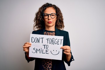 Sticker - Middle age woman holding banner with dont forget smile message over white background with a confident expression on smart face thinking serious