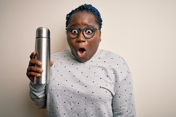 Sticker - Young african american plus size woman with braids holding thermo with coffee scared in shock with a surprise face, afraid and excited with fear expression