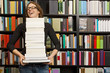 © Cavan Images - woman carrying stack of books in bookstore