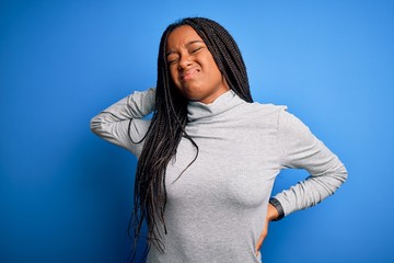 Canvas Print - Young african american woman standing wearing casual turtleneck over blue isolated background Suffering of neck ache injury, touching neck with hand, muscular pain