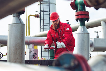 Worker adjusting gauge at oil refinery.