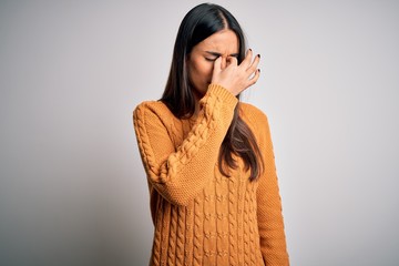 Wall Mural - Young beautiful brunette woman wearing casual sweater over isolated white background tired rubbing nose and eyes feeling fatigue and headache. Stress and frustration concept.