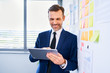 © baranq - Cheerful businessman at modern office using digital tablet