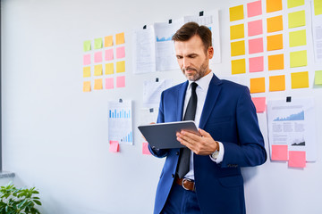 Wall Mural - Businessman in suit using digital tablet at office