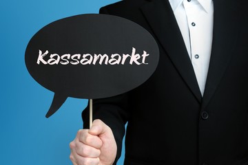 Kassamarkt. Mann im Anzug hält Sprechblase in der Hand. Der Text Kassamarkt steht im Schild. Blauer Hintergrund. Geschäftsmann für Business, Finanzen, Statistik