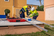 © Javier De La Torre/ADDICTIVE STOCK - Group of male technicians in uniform working with alternative solar panels and preparing for installation near residential building
