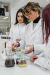 © Javier De La Torre/ADDICTIVE STOCK - Mature woman in white coat showing chemical experiment with liquid to young female trainees while working in contemporary lab