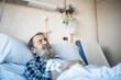 © Jos Temprano/ADDICTIVE STOCK - Calm aged man with beard lying under blanket on bed in hospital ward and sleeping