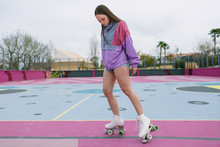 Low Angle Of Young Female In Trendy Sportswear With Quad Roller Skates Training On Colorful Playground In Spring Day