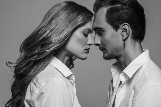 Monochrome, black and white close up studio fashion portrait of couple: beautiful woman and handsome man. Models wearing classic white shirts