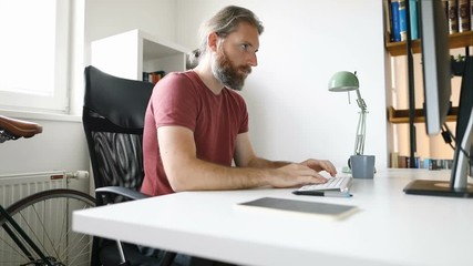 Wall Mural - Bearded man working from his home office desk