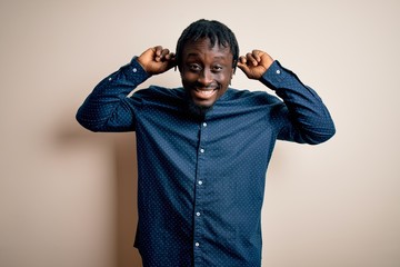 Poster - Young handsome african american man wearing casual shirt standing over white background Smiling pulling ears with fingers, funny gesture. Audition problem