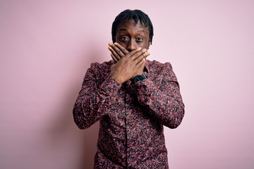 Poster - Young handsome african american man wearing casual shirt standing over pink background shocked covering mouth with hands for mistake. Secret concept.