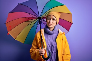 Sticker - Young blonde woman with short hair wearing waterproff raincoat and colorful umbrella with a confident expression on smart face thinking serious