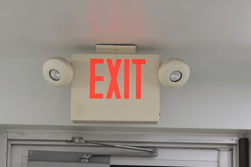 Illuminated exit sign above exterior door mounted on ceiling
