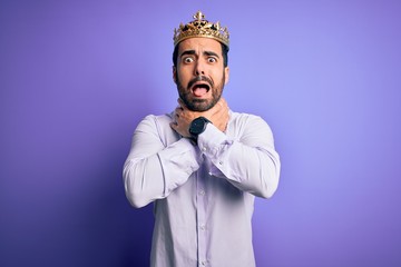 Sticker - Young handsome man with beard wearing golden crown of king over purple background shouting and suffocate because painful strangle. Health problem. Asphyxiate and suicide concept.