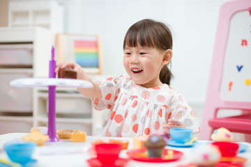 Wall Mural - toddler girl prerend play preparing tea party at home