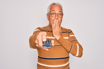 Wall Mural - Middle age senior grey-haired man using tv remote control watching television cover mouth with hand shocked with shame for mistake, expression of fear, scared in silence, secret concept