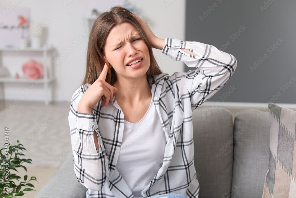 Young woman suffering from loud noise at home