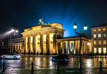 Illuminated Brandenburg Gate And Buildings In City During Rainy Season
