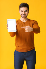 Canvas Print - Young man with tablet computer on color background